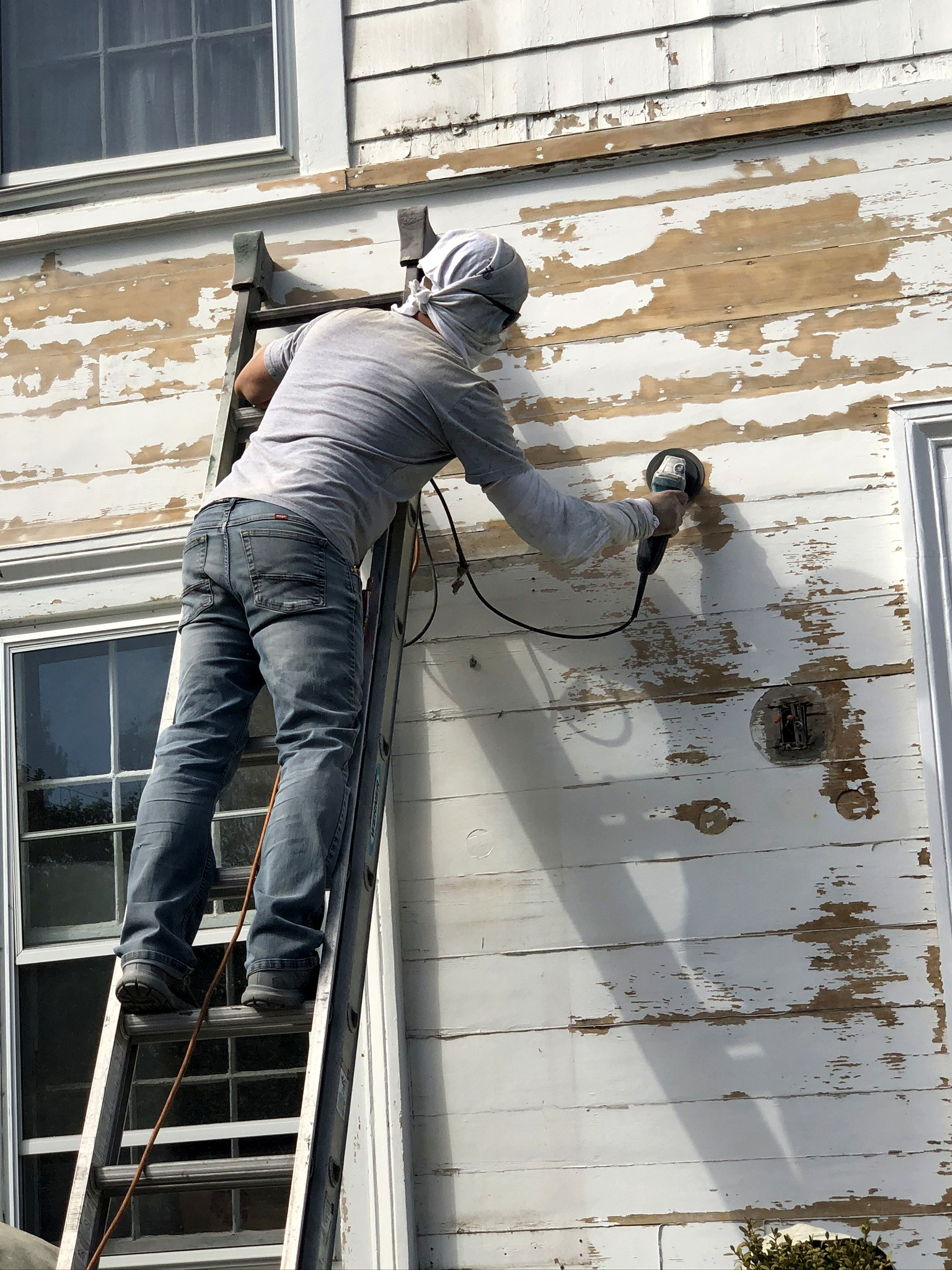 Painter scraping and prepping clapboard siding before exterior repaint in Connecticut