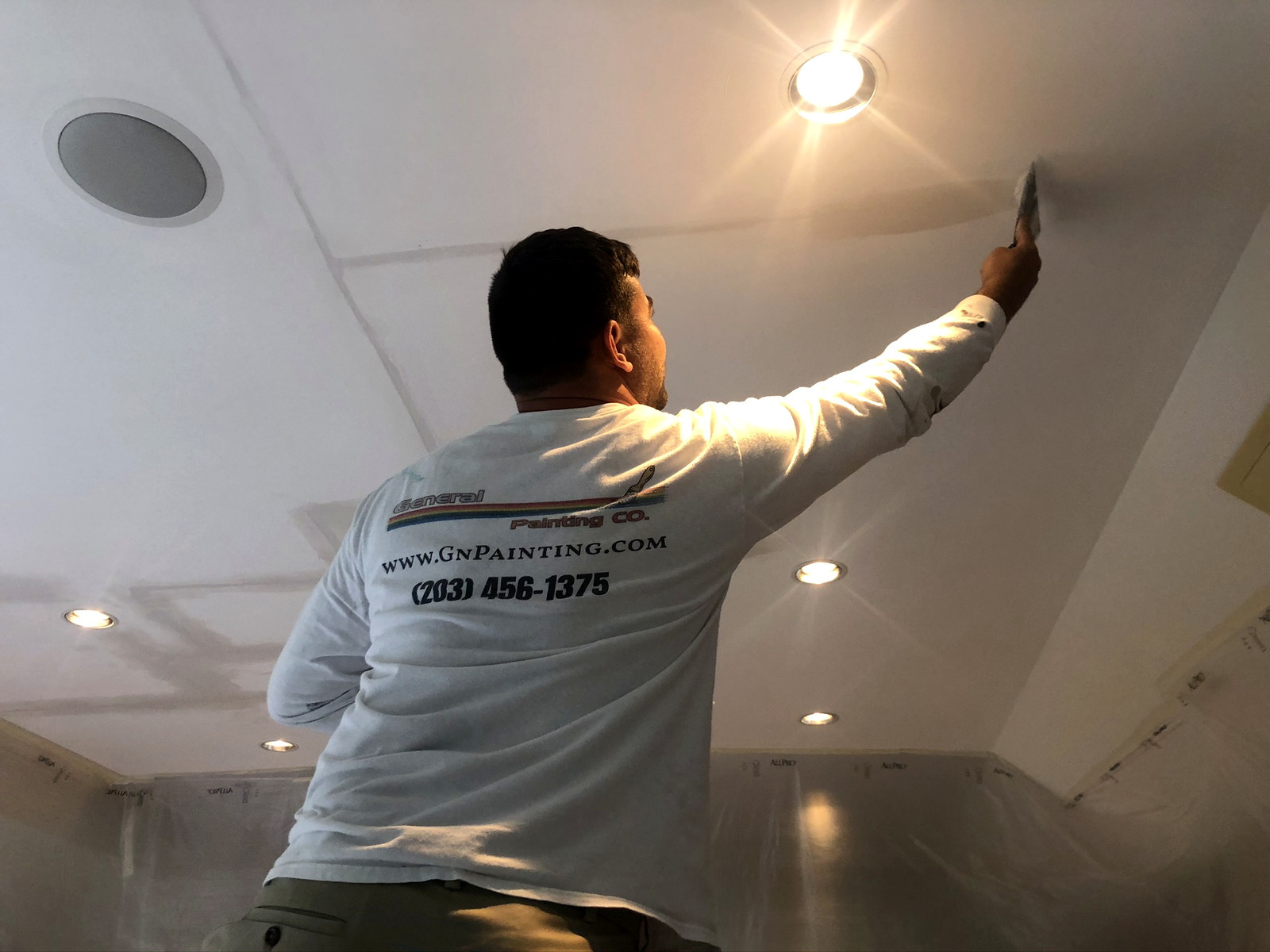General Painting Co. crew member in branded shirt cutting in ceiling — Connecticut interior project