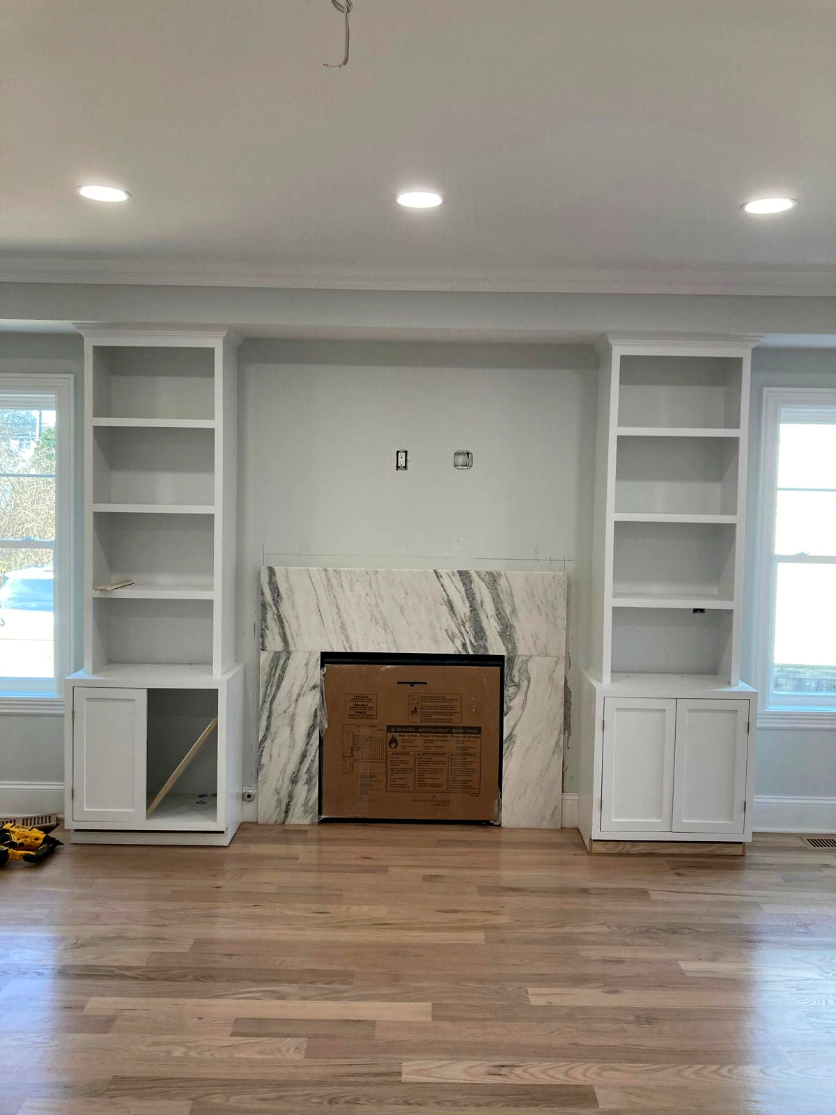 Custom white fireplace surround with built-in shelves and marble tile — Connecticut interior project