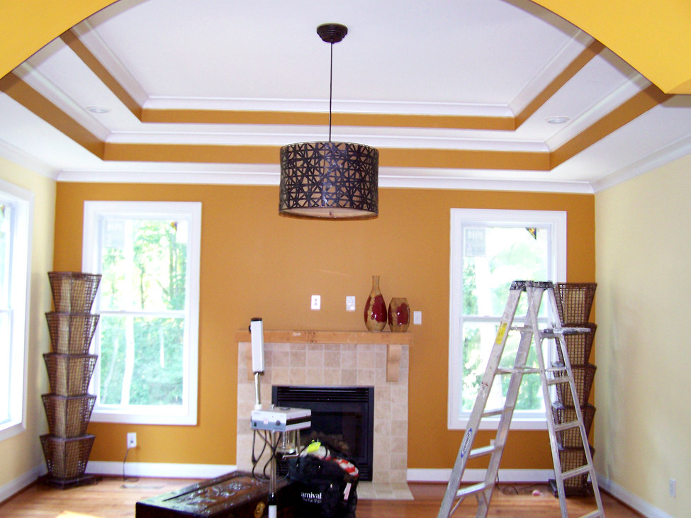 Dining room with bold gold accent walls and tray ceiling with white crown molding, Connecticut interior project